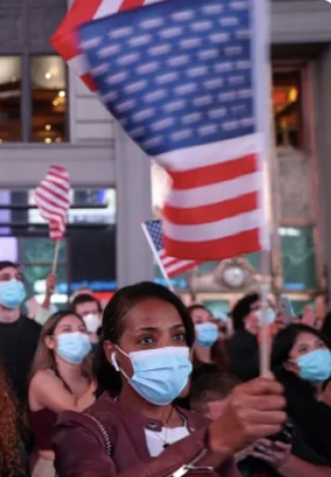 Woman wearing a face mask holds up an American flag